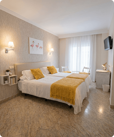 Habitación doble Habitación de hotel con una cama doble, decorada con manta y cojines de color amarillo
