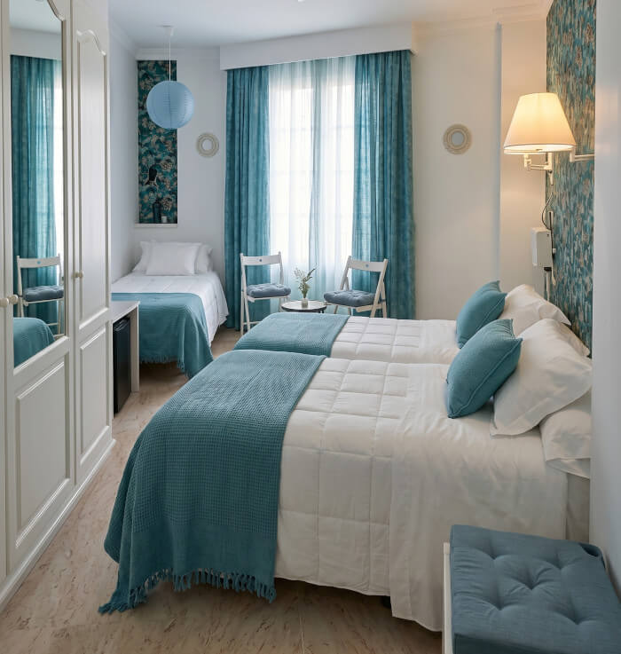 Habitación triple Habitación de hotel con una cama doble y otra individual, decoradas con manta y cojines de color turquesa